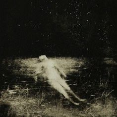 a black and white photo of a person floating in the water at night with stars above