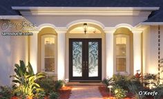 the front entrance to a house lit up at night with lights on and plants in pots