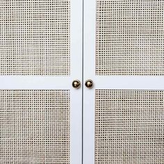 a white cabinet with two doors and some metal knobs on the front door,