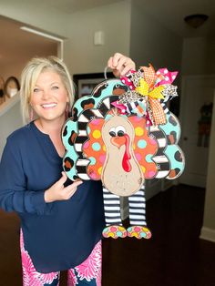 a woman holding up a turkey shaped door hanger