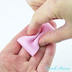 a hand holding a small pink object in it's palm