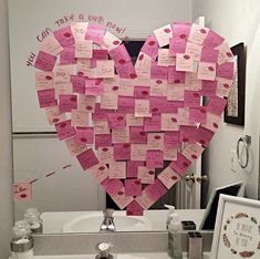 a heart made out of sticky notes on a bathroom counter top next to a mirror