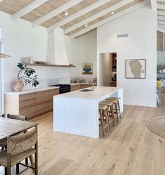 an open kitchen and dining room with white walls, wood floors and exposed beams on the ceiling