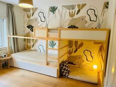 a bunk bed in a room with wooden flooring and wallpaper on the walls