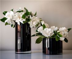 two black vases with white flowers in them