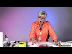 a woman in an orange shirt is sitting at a table with papers and pens on it