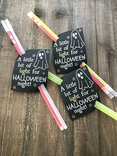 four halloween tags with glow sticks in them on top of a wooden table next to toothbrushes