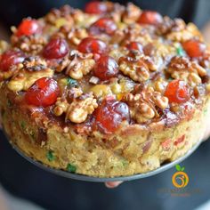 a person holding a cake with cherries and nuts