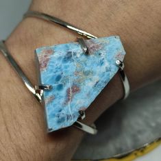 Elevate your style and gift serenity with our Raw Larimar Bracelet. This exquisite piece showcases the tranquil beauty of larimar, known for its calming blue hues and connection to the ocean. It's not just a statement piece; it's a heartfelt gift that captures the essence of relaxation and elegance. 🔸Adjustable band  🔸35mm stone size 🔸Color may vary according to lighting 🔸Silver filled We offer  🔸Fast shipping ( under normal conditions) 🔸Free shipping  🔸Polishing cloth ( to keep your piec Blue Bangle With Natural Stones For Gift, Gift Blue Bangle With Natural Stones, Natural Stones Bangle As A Gift, Adjustable Fusion Style Sterling Silver Bracelet For Gift, Unique Natural Stones Bangle As Gift, Unique Bangle With Natural Stones For Gift, Unique Bangle With Natural Stones As Gift, Larimar Bracelet Jewelry Gift, Silver Larimar Bracelets As Gift