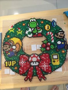 a christmas wreath made out of legos is being displayed on a wooden table next to a notebook