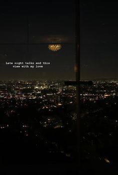 the city lights are lit up at night and there is a quote written on the window