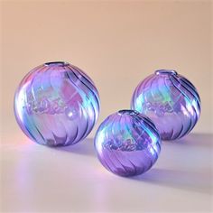 three purple glass vases sitting on top of a table