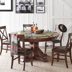 a dining room table with four chairs and pictures on the wall above it, along with other furniture