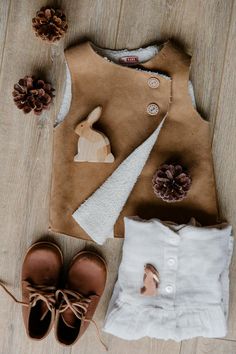 a pair of brown shoes sitting on top of a wooden floor next to a white shirt