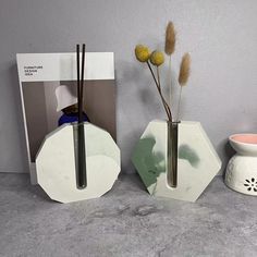 three vases with flowers in them sitting next to a book and magazine on a table