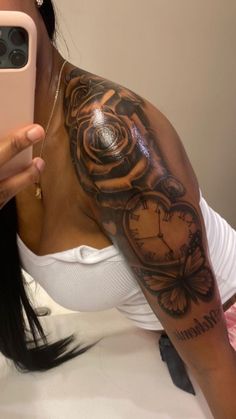 a woman taking a selfie with her cell phone and clock tattoo on her arm