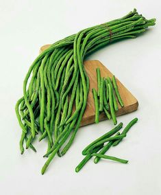 green beans are on a cutting board and ready to be cooked