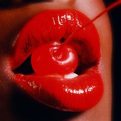 a woman's lips with a cherry in the middle of her lip and an object sticking out of it