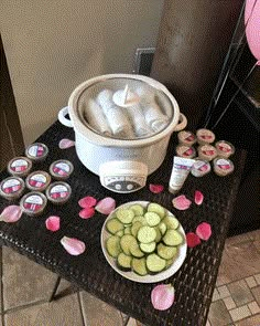 a table topped with cucumbers and cupcakes next to a crock pot