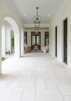 an empty hallway with white tile floors and black shutters on both sides, leading to the front door