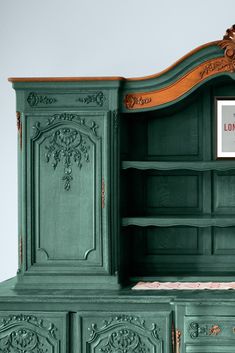 an old fashioned green painted dresser with ornate carvings on the doors and drawers, has a sign that says london