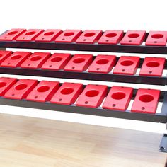 three tiered rack with red and black plastic objects on it's sides in front of a white background