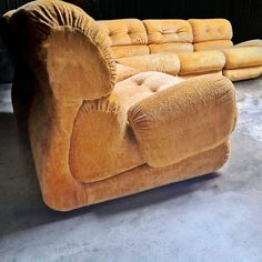 two couches sitting next to each other in a room with concrete floors and walls