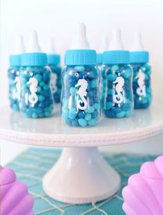 blue and white baby bottles with seahorses on them sitting on a cake plate