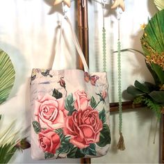 a pink rose print bag hanging from a hook on a wall next to green plants