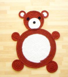 a crocheted teddy bear rug on a wooden floor