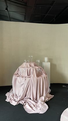 a pile of wine glasses sitting on top of a table covered in pink cloths