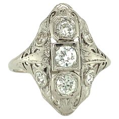 This vintage Art Deco ring, crafted in 14K white gold, showcases intricate filigree work and seven bead-set, old European cut diamonds totaling 0.64 carats. With L-M color and SI-1 clarity, these diamonds exude a soft, timeless brilliance that complements the hand-made details of the ring. Measuring 22 mm long upon the finger, the design creates an elegant, elongated silhouette that captures the essence of 1930s craftsmanship. Stamped "14K” and weighing 3.2 grams, this size 7 ring embodies the r 14k White Gold Diamond Ring, Vintage Art Deco Rings, 7 Ring, 1930s Art, Art Deco Stil, Bead Set, White Gold Diamond Rings, Deco Ring, European Cut Diamonds