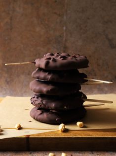 a stack of chocolate covered donuts sitting on top of a cutting board next to nuts