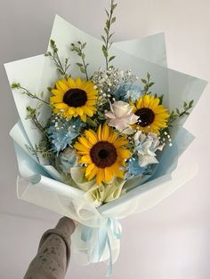 a bouquet of sunflowers and baby's breath is being held by a person