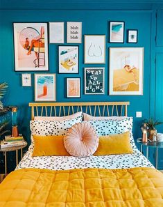 a bedroom with blue walls and pictures on the wall above the bed, along with a yellow bedspread