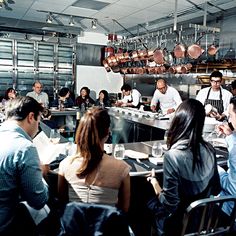 a group of people sitting at a table in a restaurant with pots and pans hanging from the ceiling