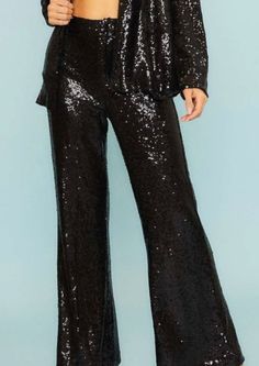 a woman wearing black sequin pants and a crop top