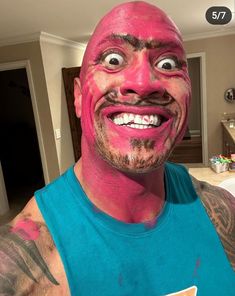 a man with pink paint on his face and chest smiling at the camera while wearing a blue shirt