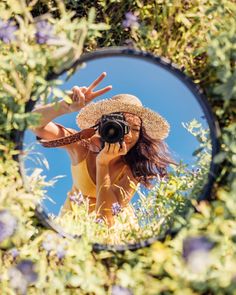 a woman taking a selfie in front of a mirror with purple flowers around her