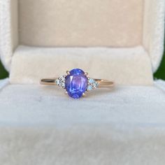 a tan gold ring with an oval blue sapphire surrounded by three white diamonds in a box