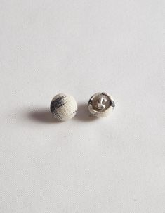 two white and black beads sitting on top of a white cloth covered table next to each other