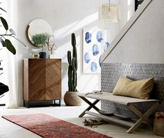 a living room filled with furniture next to a stair case and potted cactus in the corner