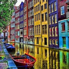 several boats are parked on the side of a river in front of some colorful buildings