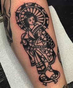 a tattoo on the leg of a person with a geisha doll and an umbrella