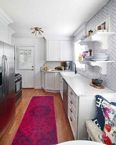 a kitchen with white cabinets and red rugs on the floor, along with stainless steel appliances