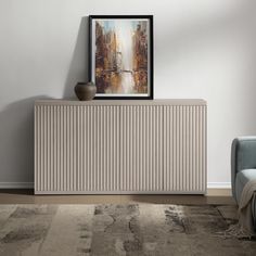 a white cabinet sitting next to a blue chair in a room with a painting on the wall