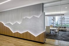 an office with wooden floors and white walls, along with mountains on the wall behind it