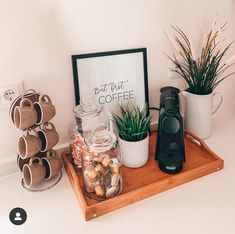 there is a coffee maker on the counter next to some cups and mugs with plants in them