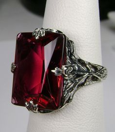 Simulated Ruby Ring GL Design#15 Made to Order This is a brand new 1930s reproduction solid sterling silver 925 floral leaf filigree approx. 10ct Simulated/man-made ruby gemstone ring. The inside of the band is hallmarked 925 for sterling. This rectangle-cut gemstone is 16mm (5/8th of an inch) by 12mm (1/2 inch) in size. Notice the beautiful leaf design of the silver filigree setting. This is an exquisite rendition of an antique filigree ring... and is ready to wear. A ring gift box is included. Leaf Filigree, Floral Filigree, Antique Filigree, Filigree Jewelry, Art Deco Stil, Ruby Earrings, Filigree Ring, Ruby Gemstone, Engraved Items