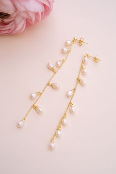 Add a touch of graceful elegance to your bridal look with the Whispering Pearl Drop Earrings! These stunning dangle earrings feature freshwater pearls delicately hanging from a fine gold chain, creating a perfect balance of timeless beauty and modern sophistication. Why do we love them? They’re the perfect blend of chic and classic beauty, making them a must-have for your special day! EARRING FEATURES Material: Brass, Freshwater Pearls Dimensions/Size: 3.2" drop Finish: Polished 14k Gold Plating Delicate 14k Gold Filled Earrings With Pearl Chain, Delicate Pearl Chain Dangle Earrings, Delicate Long Drop Pearl Earrings In 14k Gold, Delicate Gold Pearl Chandelier Earrings, Dainty Long Drop Linear Earrings With Pearl Drop, Gold Pearl Chandelier Earrings Delicate Style, Elegant 14k Gold Filled Pearl Drop Earrings, Gold Pearl Chandelier Earrings In Delicate Style, Gold Plated Pearl Chain Dangle Earrings